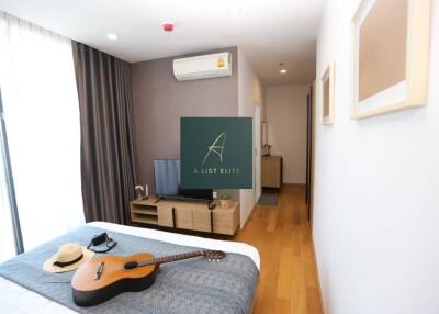 Bedroom with natural light, modern decor, and guitar on the bed