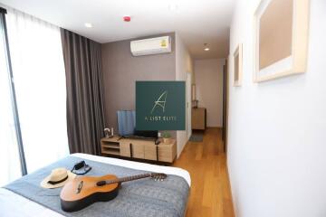 Bedroom with natural light, modern decor, and guitar on the bed