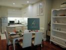 Modern kitchen and dining area with white cabinetry and wooden flooring