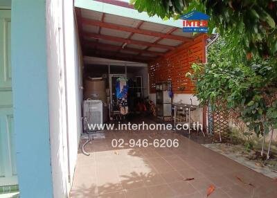 Covered outdoor area with a washing machine and hanging clothes.