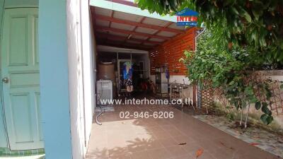 Covered outdoor area with a washing machine and hanging clothes.