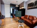 A modern living room with wooden flooring, leather sofa, marble coffee table, and wall art