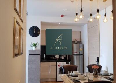 Modern kitchen and dining area with wooden flooring, paintings, and decorative lighting.