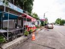 Street side with a food stall, car parked, and greenery