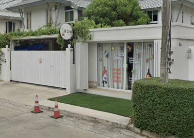 Exterior view of a white residential house with a gated entrance