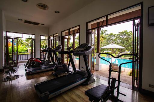 Home gym with exercise equipment and view of swimming pool