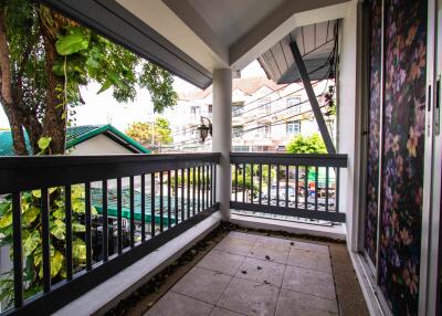 Spacious balcony with railing and a view of nearby buildings and greenery