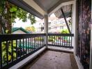 Spacious balcony with railing and a view of nearby buildings and greenery