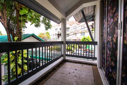 Spacious balcony with railing and a view of nearby buildings and greenery