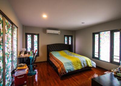 spacious bedroom with bed, desk, and bright windows