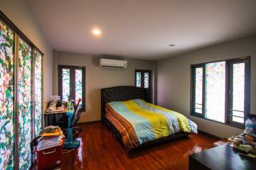 spacious bedroom with bed, desk, and bright windows