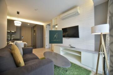 Modern living room with a sofa, TV, coffee table, and dining area in view