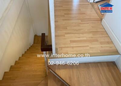 Indoor wooden stairs leading up to a wooden landing area.