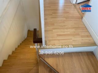 Indoor wooden stairs leading up to a wooden landing area.