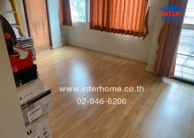 Empty bedroom with wooden flooring and window with orange curtains