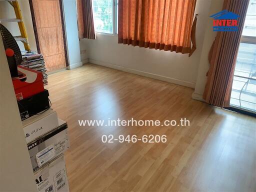 Empty bedroom with wooden flooring and window with orange curtains