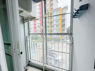 View of balcony with glass doors overlooking urban apartment buildings