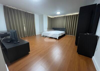 Spacious bedroom with wooden flooring, a large bed, and ample natural light