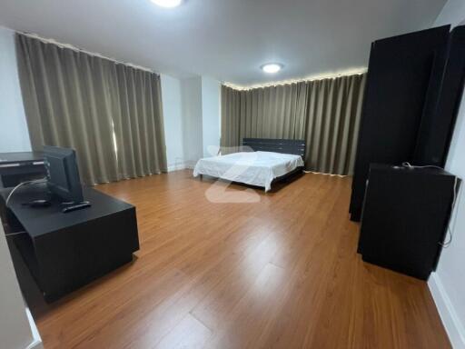 Spacious bedroom with wooden flooring, a large bed, and ample natural light