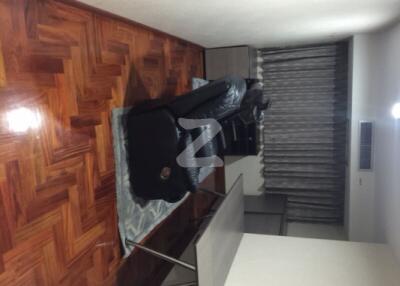 Living room with wooden flooring, black couch, and curtains