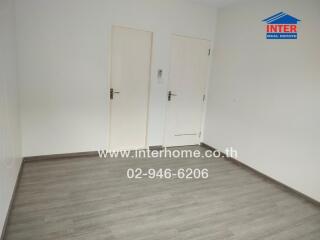 Bright empty bedroom with wooden flooring and closed doors