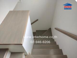 Staircase with wooden steps and white walls