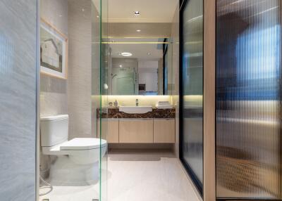 Modern bathroom with toilet, sink, and glass partition