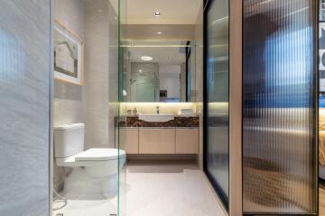 Modern bathroom with toilet, sink, and glass partition