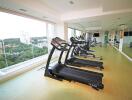 A modern gym with treadmills and large windows offering a scenic view.