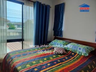 A cozy bedroom with colorful bedding and large windows