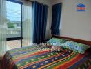 A cozy bedroom with colorful bedding and large windows