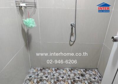 Shower area with tiled floor and wall-mounted shower head