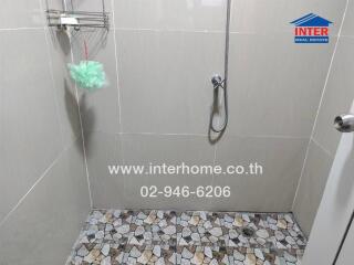 Shower area with tiled floor and wall-mounted shower head