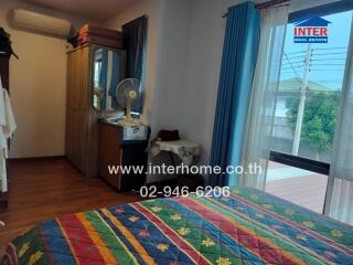 Bedroom with colorful bedding, wardrobe, and a window