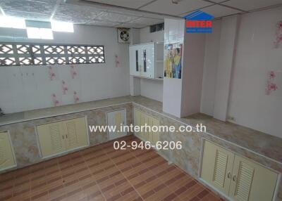 Kitchen with light yellow cabinets, tiled floor, and floral wall decals