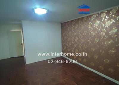 Interior view of a decorated room with wooden flooring and patterned wallpaper