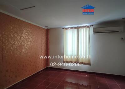 Empty bedroom with patterned orange wall and large window with curtain