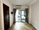 Bright main living area with wood flooring and access to a balcony