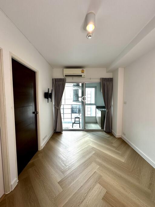 Bright main living area with wood flooring and access to a balcony