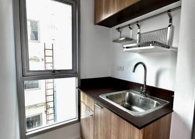 Compact modern kitchen with wooden cabinets and a large window