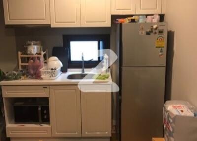 Compact kitchen with white cabinets and stainless steel refrigerator