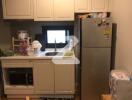 Compact kitchen with white cabinets and stainless steel refrigerator