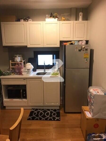 Compact kitchen with white cabinets and stainless steel refrigerator