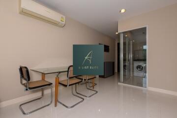 Modern dining area with glass table and washer/dryer in the background