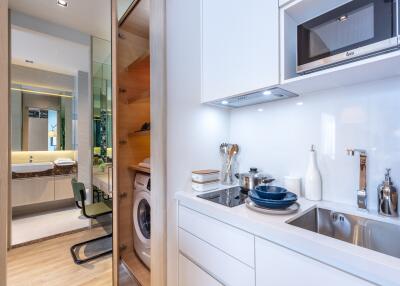 Modern kitchen with white cabinets and appliances, view of the laundry area and bathroom