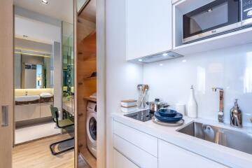 Modern kitchen with white cabinets and appliances, view of the laundry area and bathroom