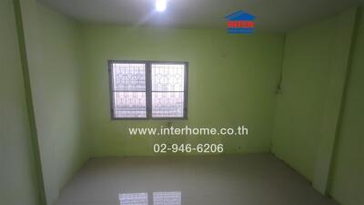 Empty bedroom with tiled floor and barred window