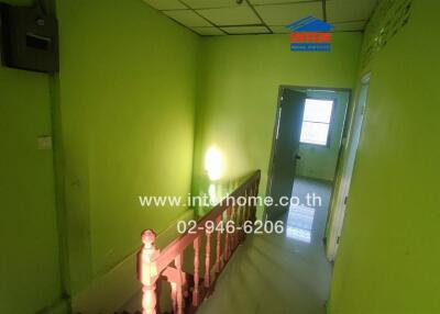 Green hallway with staircase and a door