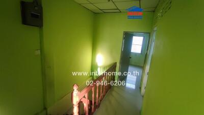 Green hallway with staircase and a door