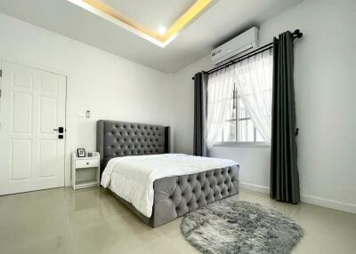 Modern bedroom with gray tufted bed and large window